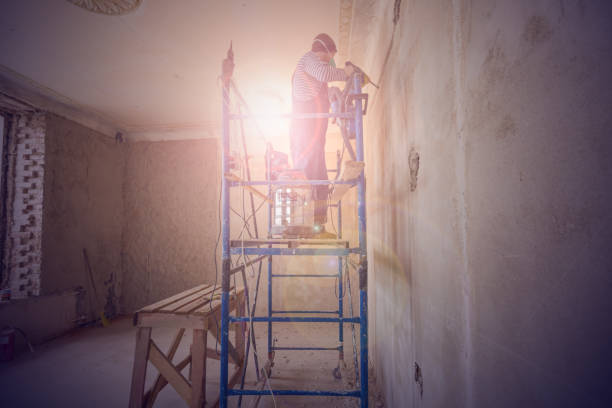 arbeiter macht ein technologisches loch für elektrische kabel in der wand in der wohnung, die sich im bau, umbau, renovierung, erweiterung, restaurierung und wiederaufbau befindet - restoring scaffolding built structure home improvement stock-fotos und bilder