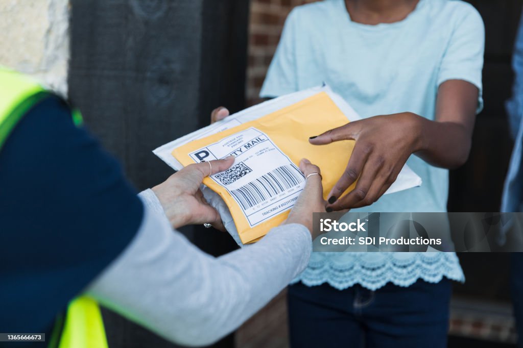 Focus on unrecognizable girl receiving packages from unrecognizable mail person The focus of the photo is on the hands of an unrecognizable young girl as she receives packages from the hands of an unrecognizable female delivery person. Delivering Stock Photo