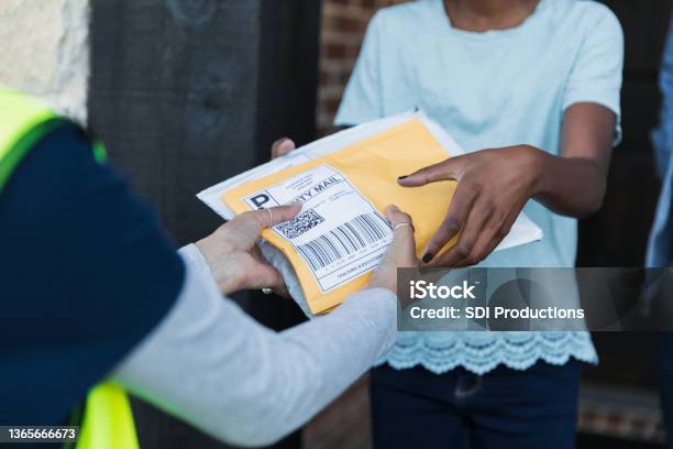 Focus On Unrecognizable Girl Receiving Packages From Unrecognizable Mail Person Stock Photo - Download Image Now