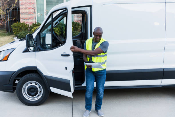 istock Driver looks at package while closing door of van 1365666674
