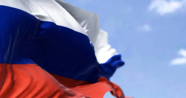 Detail of the national flag of Russia waving in the wind on a clear day. Democracy and politics. Largest country in the world. Selective focus.