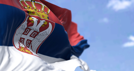 Detail of the national flag of Serbia waving in the wind on a clear day. Democracy and politics. European country. Selective focus.