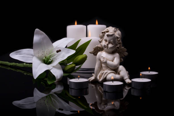 istock White angel with candles and white lily flower on a black background 1365667005