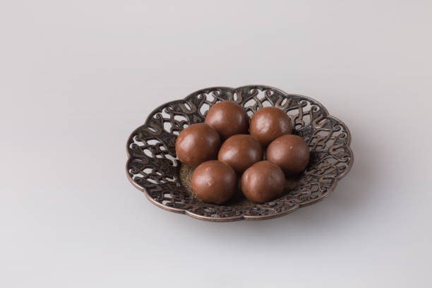 Chocolate candy balls. Delicious dessert on a plate on a light background. Sweets on a carved oriental saucer.