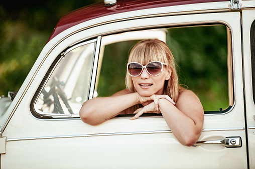 Young woman looking through a vintage car window
