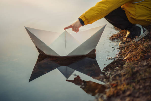 istock a child, a boy, launches a paper boat into the water 1365669590