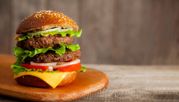 istock Tasty burger with cheese on wooden table 1365671273