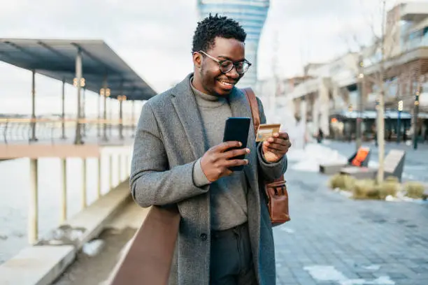 Photo of Afro american businessman using smart phone on city street