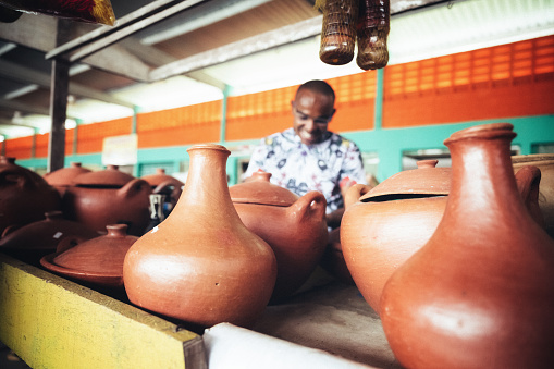 young market vendor behind his pottery stall at public market in Bahia, Brazil, focus on foreground