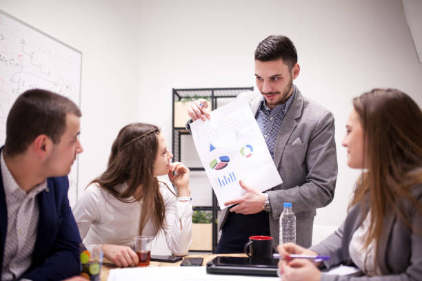 istock Successful young architects in modern workplace, having a creative meeting. Group leader presenting graphs and pie charts 1365672833