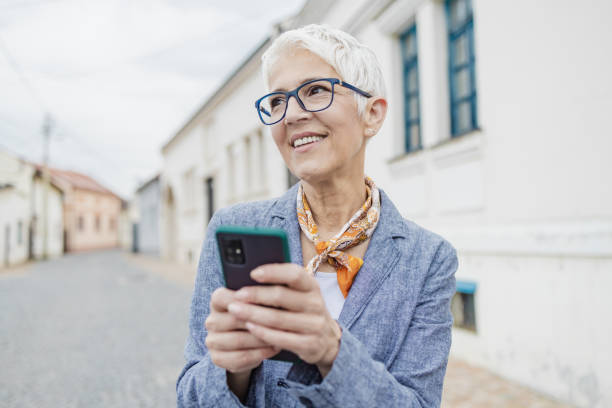 istock Senior woman is using mobile phone on the street 1365674988