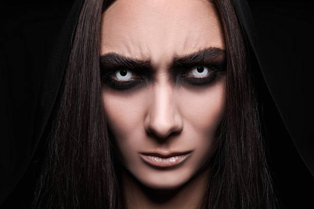 istock Mysterious witch with spooky eyes on black background, closeup 1365677602