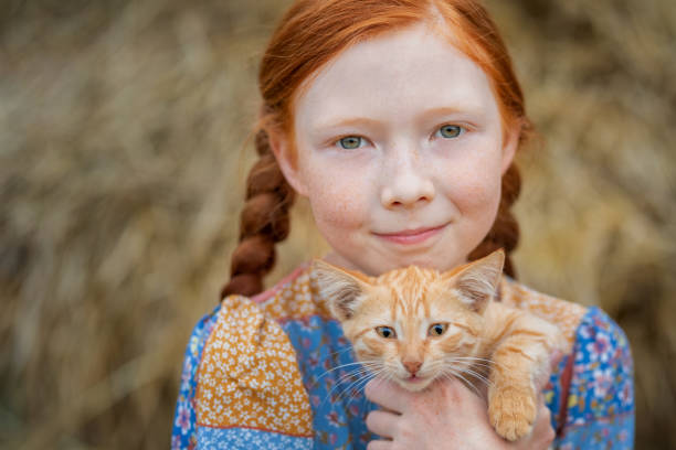 redhead girl holding a ginger kitten in her arms