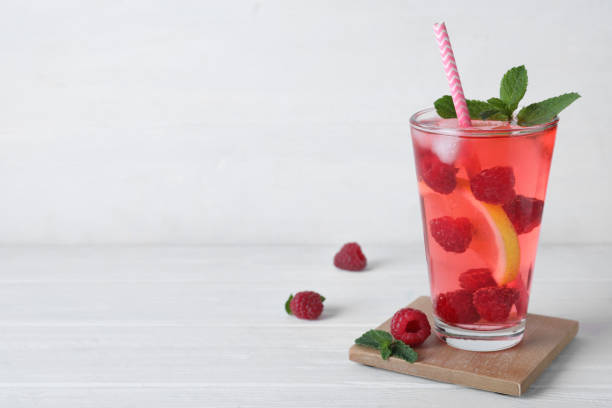 istock Delicious raspberry lemonade made with soda water and ingredients on white wooden table. Space for text 1365679098