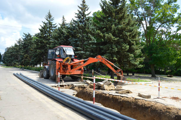 istock tractor, trench and new plumbing plastic pipes. new plumbing work 1365679207