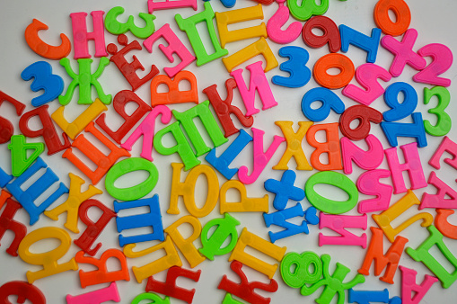 multi-colored magnetic letters of the Russian alphabet on a white board. letters are arranged in a random order. teaching literacy to children of preschool and school age