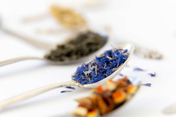 Green, cornflower and orange tea in metal spoons