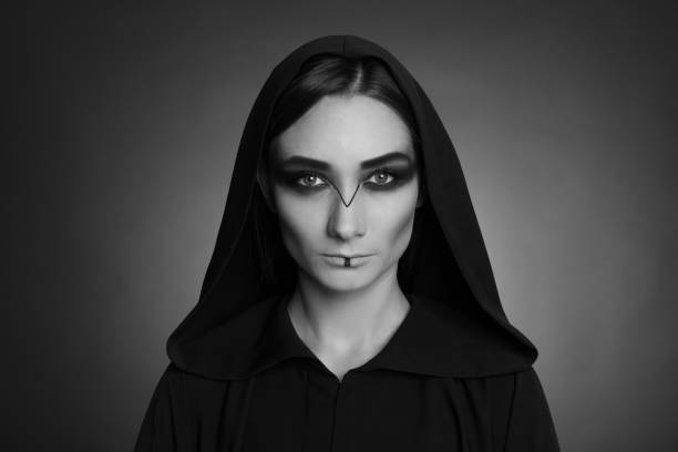 istock Mysterious witch in mantle with hood on dark background. Black and white effect 1365680954