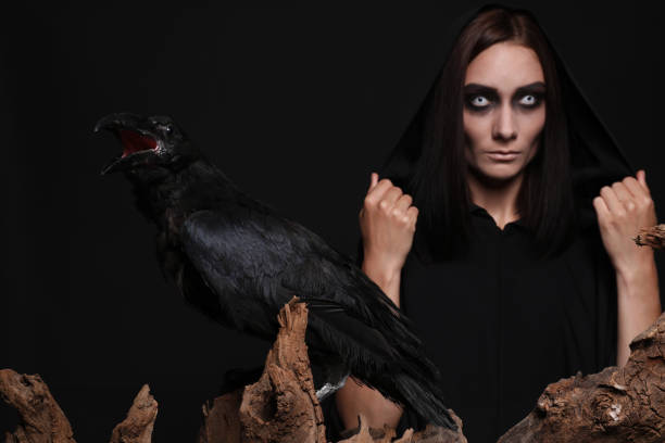 istock Raven and mysterious witch on black background 1365682367