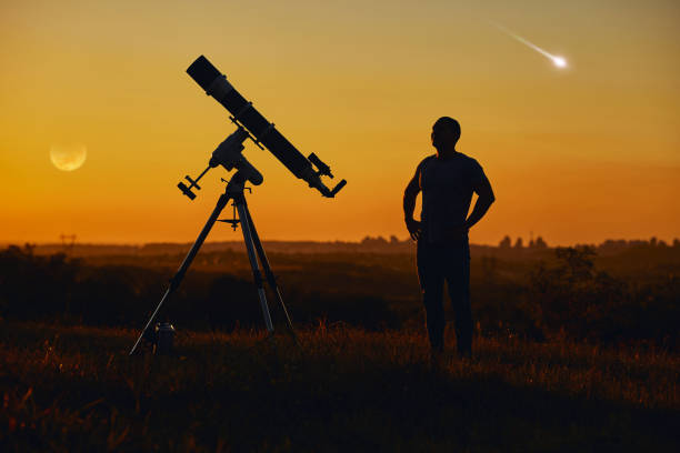 istock Silhouette of a man, astronomical telescope, countryside, lunar eclipse and meteor shower. 1365684797