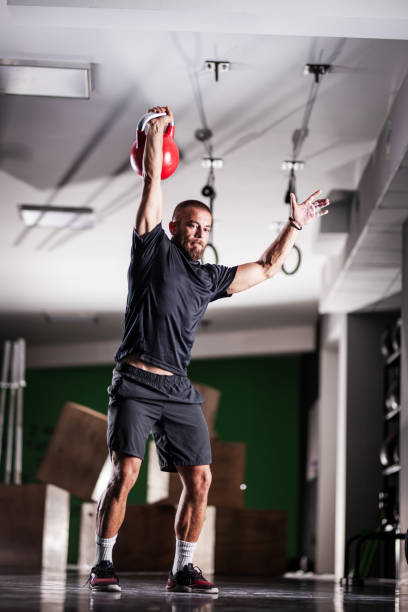 istock Muscular athlete power lifting a kettlebell. Man working out indoors 1365686237