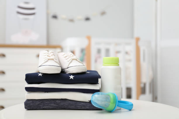 istock Stack of baby clothes, shoes and accessories on white table indoors 1365687719