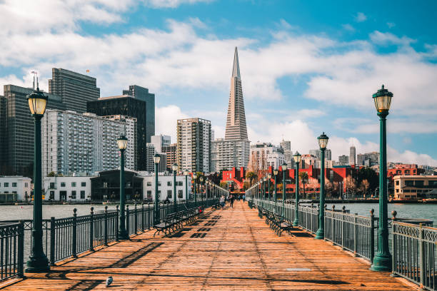Beautiful view of San Francisco San Francisco, USA - January 26, 2020: Beautiful panoramic view of business finance center and waterfront of metropolis. High-rise buildings. Fence, benches and vintage lampposts along pier. transamerica pyramid san francisco stock pictures, royalty-free photos & images