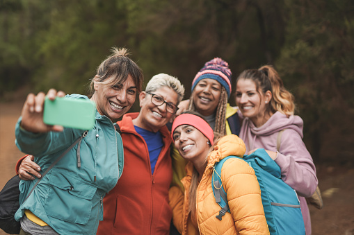 Multiracial women having fun taking a selfie using mobile phone during  trekking day - Multi generational people enjoy day outdoor