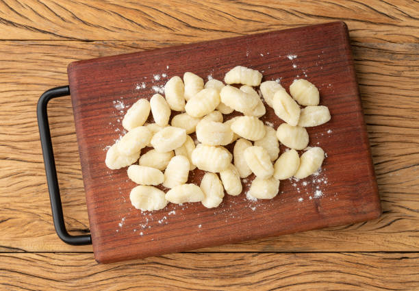 istock Uncooked italian pasta gnocchi on a board over wooden table 1365689539