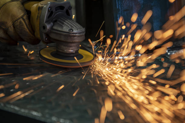 istock Streaking sparks arcing out and past camera, as worker grinds away at steel weld with angle grinder tool, its sanding disk glowing with heat 1365692239