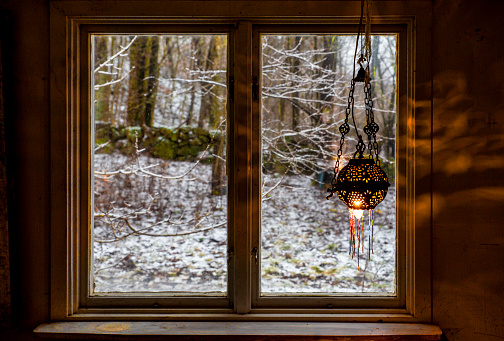 Window in a old house with bright light shining from a vintage lamp, throws lightflares on the wall