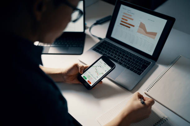 istock Mid adult man checking financial information on a smart phone while doing his bookkeeping 1365692465