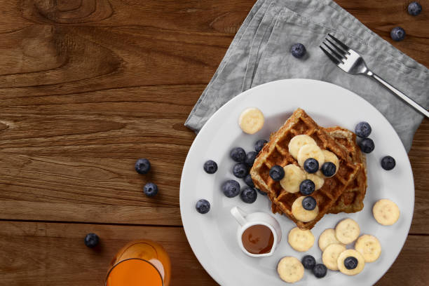 Oatmeal Belgian waffles topped with banana and blueberry on rustic wooden table. Healthy breakfast diet recipe