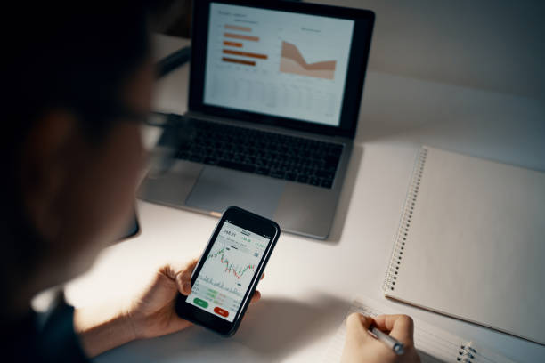 istock Mid adult man checking financial information on a smart phone while doing his bookkeeping 1365692509