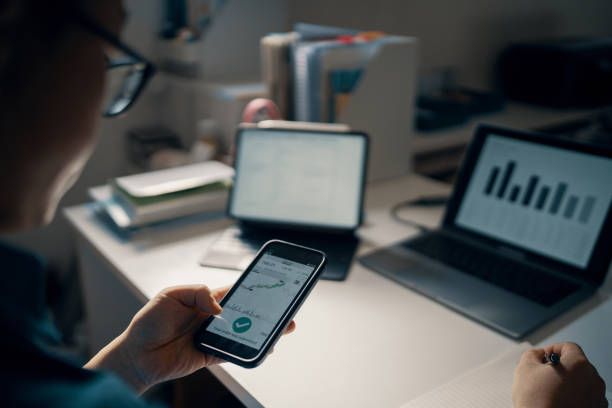 istock Mid adult man checking financial information on a smart phone while doing his bookkeeping 1365692548