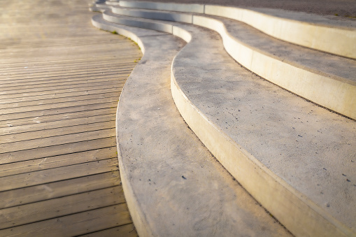 A contemporary stairdesign wave, all made in concrete, aligned to a wooden deck