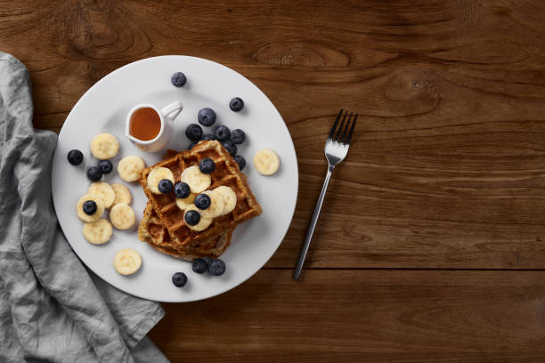 Oatmeal Belgian waffles topped with banana and blueberry on rustic wooden table. Healthy breakfast diet recipe