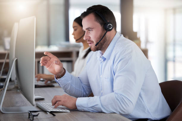 istock Shot of a young call centre agent working on a computer in an office at night 1365699517
