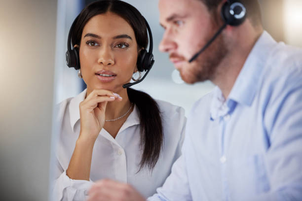 istock Shot of two call centre agents working together on a computer in an office at night 1365699586