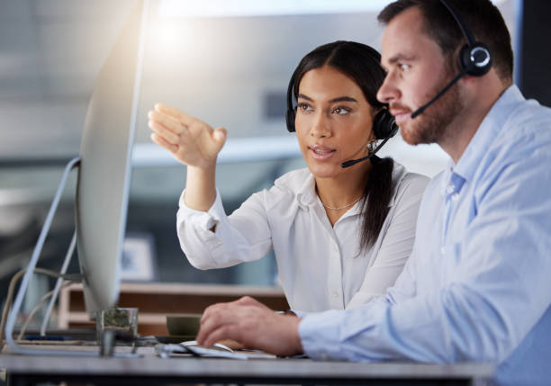 istock Shot of two call centre agents working together on a computer in an office at night 1365699600