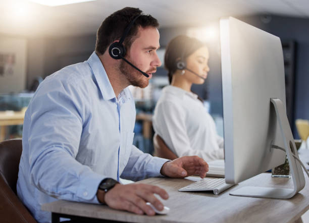 istock Shot of a young call centre agent working on a computer in an office at night 1365699619