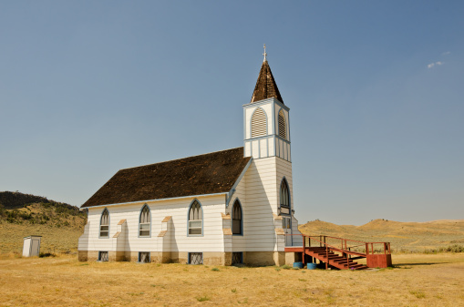 Little white church with blue trim in rural Montana still has an outhouse in the back