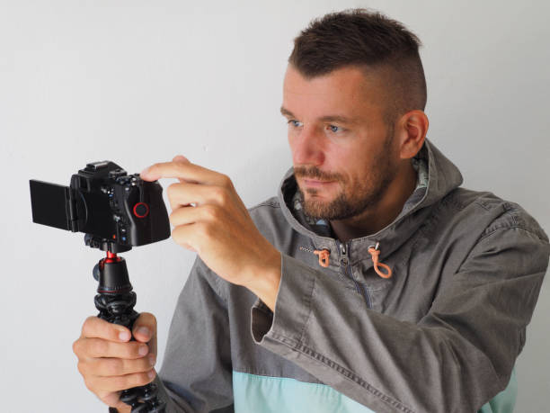 istock Man video blogger pushing button on mirrorless camera with mic, to start recording herself. Close-up. 1365703774