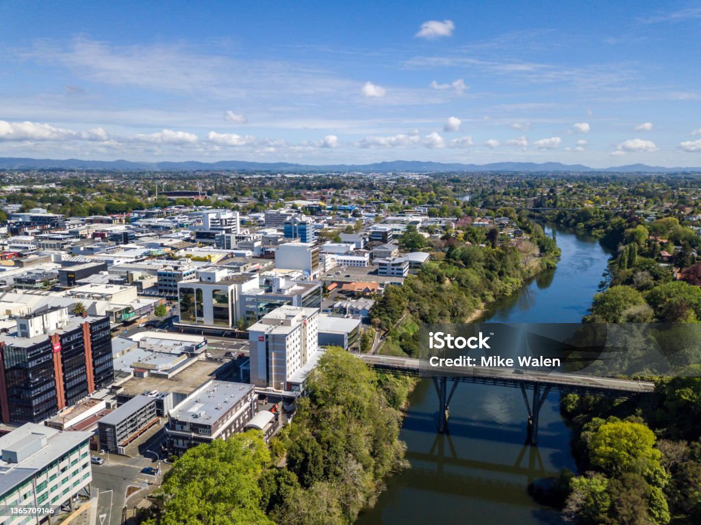 Aerial drone view of Hamilton City (Kirikiriroa) in the Waikato Region of New Zealand, Aotearoa Aerial view looking over the central business district from the Waikato River as it cuts through the city of Hamilton, in Waikato, New Zealand. Claudelands Bridge visible. New Zealand Stock Photo