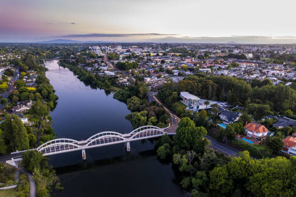 Aerial drone view at sunset of Hamilton City (Kirikiriroa) in the Waikato Region of New Zealand, Aotearoa A drone captured view looking towards the central business district (CBD) from the Fairfield Bridge over the Waikato River as it cuts through the city of Hamilton, in Waikato, New Zealand. waikato river stock pictures, royalty-free photos & images