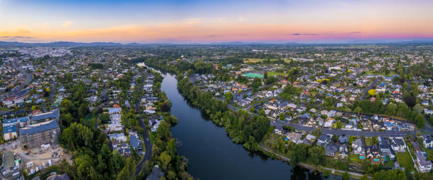 Aerial panoramic drone view at sunset of Hamilton City (Kirikiriroa) in the Waikato Region of New Zealand, Aotearoa A drone captured view looking towards Hamilton North from the Fairfield Bridge over the Waikato River as it cuts through the city of Hamilton, in Waikato, New Zealand. waikato river stock pictures, royalty-free photos & images