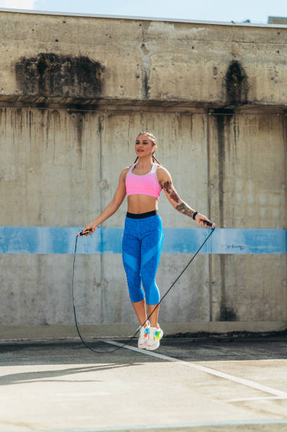istock Attractive young woman using a fitness jump rope while training outside 1365709764