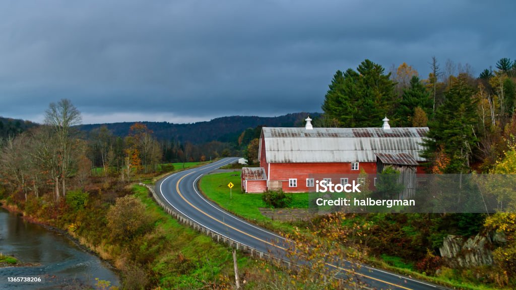 Barn in Rural Vermont - Aerial Drone shot of  a rural scene in Caledonia County, Vermont on a rainy day in Fall, looking down on fields and farms in a valley near Hardwick, with mountains covered in an autumnal forest receding into the misty distance. Red Barn Stock Photo