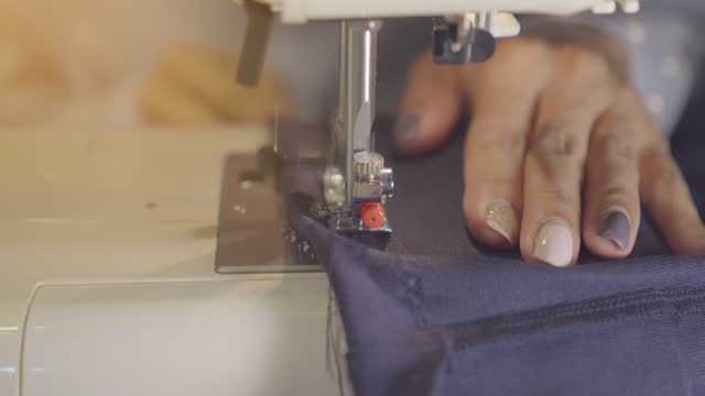 Female hands with denim on the sewing machine, close-up. The concept of clothing repair, recycling, home hobbies and work at home.