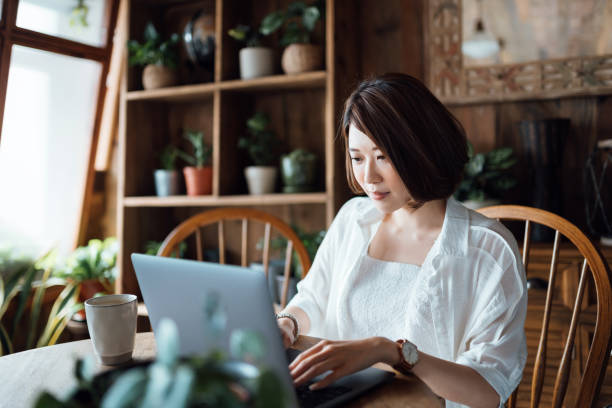 istock Young Asian businesswoman using a laptop while working in her home office. Remote working, freelancer, small business concept 1365749350